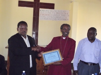 Bishop Mwita giving Dr Muniko a Certificate of Appreciation